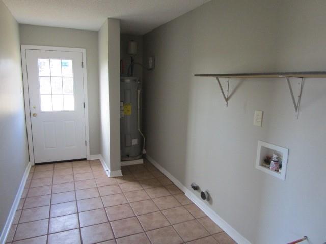 laundry room featuring electric water heater, light tile patterned floors, and washer hookup