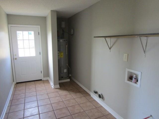 washroom with washer hookup, electric water heater, and light tile patterned flooring