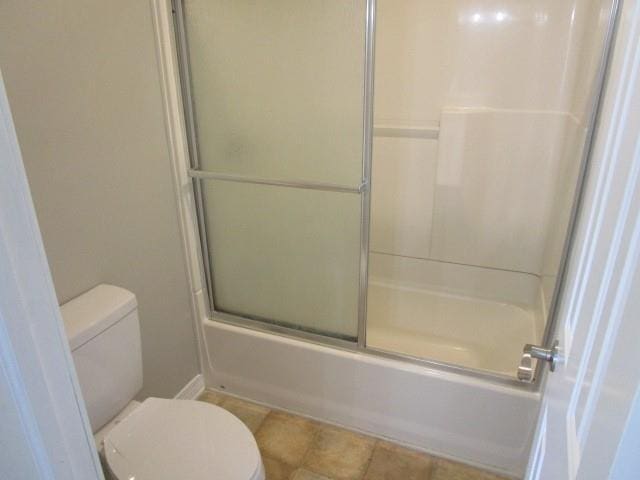 bathroom with toilet and combined bath / shower with glass door