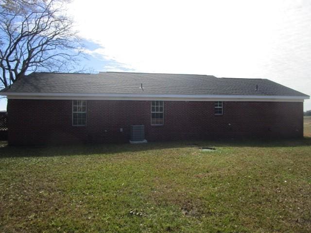 rear view of house featuring a yard and central air condition unit