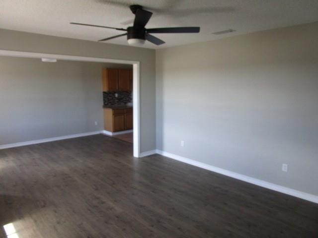 unfurnished room featuring ceiling fan and dark wood-type flooring