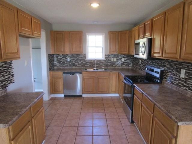 kitchen with backsplash, sink, light tile patterned floors, and appliances with stainless steel finishes