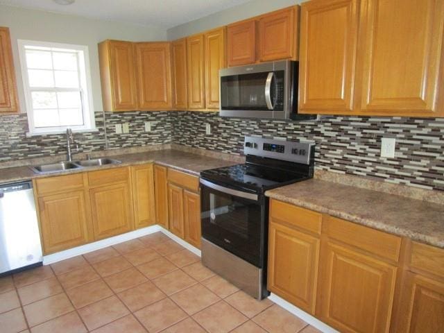 kitchen with light tile patterned flooring, sink, appliances with stainless steel finishes, and tasteful backsplash