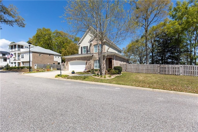 traditional-style home with a front lawn, driveway, an attached garage, and fence