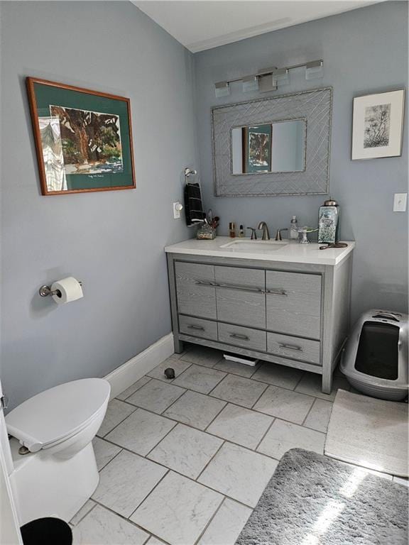 bathroom with baseboards, toilet, and vanity