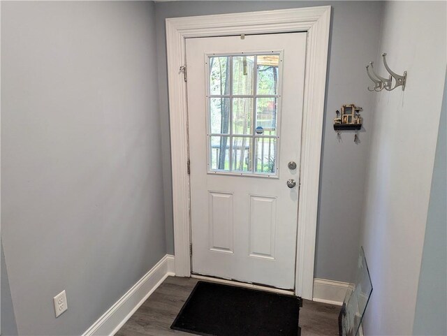 doorway with baseboards and dark wood-style flooring