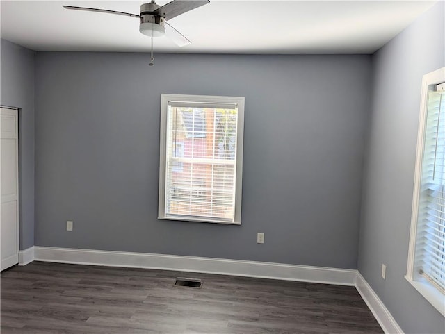 unfurnished room with visible vents, baseboards, dark wood-style flooring, and ceiling fan