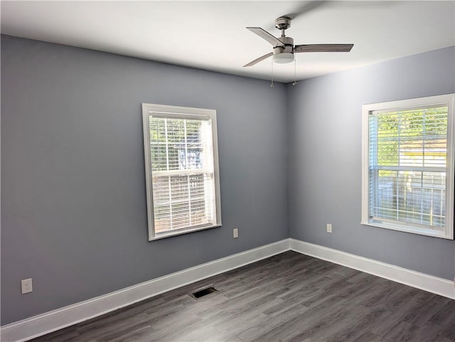 empty room featuring visible vents, baseboards, ceiling fan, and dark wood-style flooring