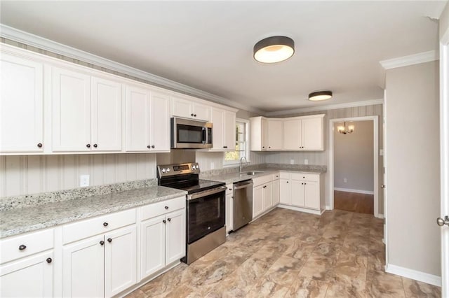 kitchen featuring light stone counters, crown molding, stainless steel appliances, white cabinetry, and a sink