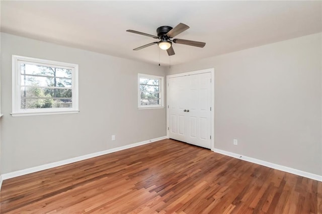 empty room with a ceiling fan, baseboards, and wood finished floors