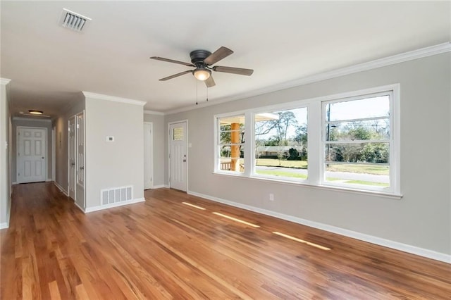 unfurnished living room featuring ornamental molding, visible vents, and baseboards