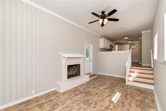 unfurnished living room featuring ornamental molding, a fireplace, baseboards, and a ceiling fan