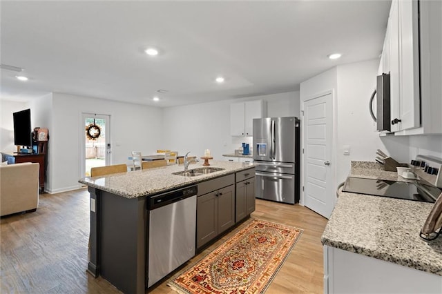 kitchen featuring appliances with stainless steel finishes, white cabinetry, a center island with sink, and sink