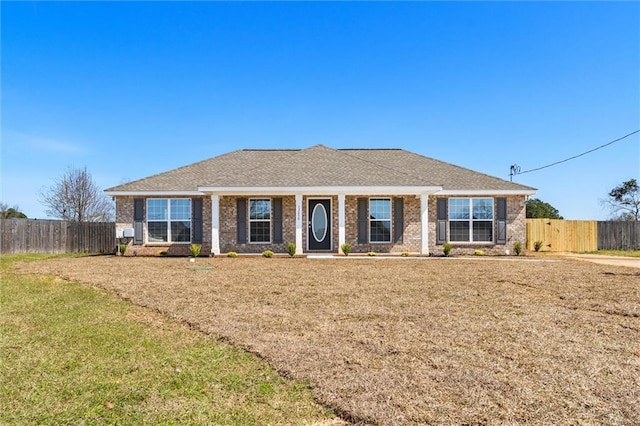 ranch-style house featuring a front lawn, fence, and brick siding