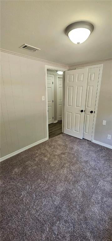 unfurnished bedroom with crown molding and dark colored carpet