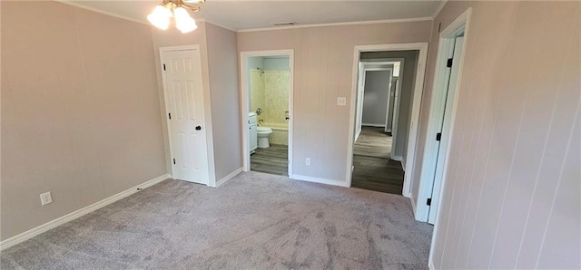 unfurnished bedroom featuring ornamental molding, ensuite bath, and carpet floors