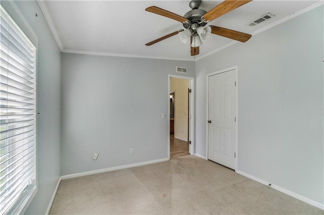 unfurnished bedroom featuring light carpet, baseboards, visible vents, and crown molding