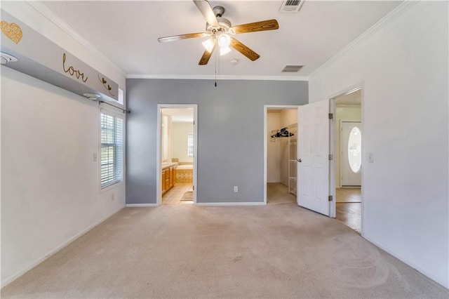 unfurnished bedroom featuring a spacious closet, light colored carpet, visible vents, and crown molding