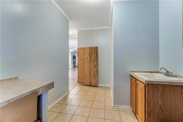 bathroom featuring baseboards, tile patterned flooring, a textured ceiling, crown molding, and a sink