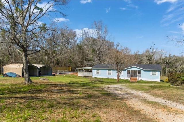 exterior space featuring dirt driveway, a carport, and a front lawn