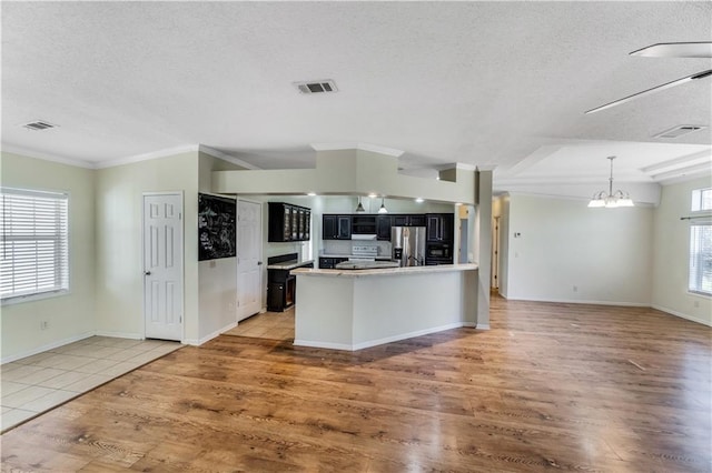 kitchen featuring light wood finished floors, visible vents, stainless steel appliances, and dark cabinets