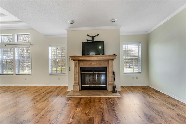 unfurnished living room featuring plenty of natural light, baseboards, wood finished floors, and a glass covered fireplace