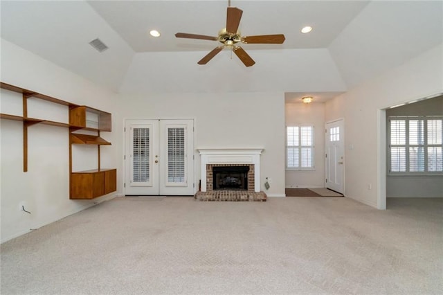 unfurnished living room with french doors, light colored carpet, a fireplace, and ceiling fan