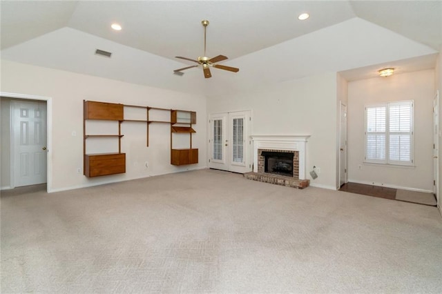 unfurnished living room featuring ceiling fan, light colored carpet, a fireplace, and vaulted ceiling