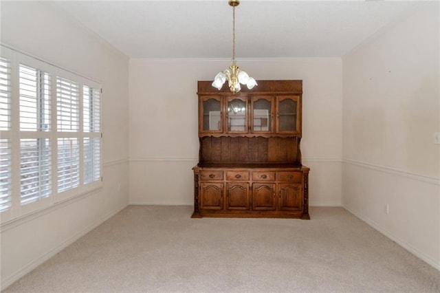 carpeted empty room featuring crown molding and a chandelier