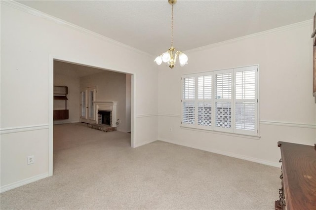 empty room featuring crown molding, a brick fireplace, light colored carpet, and an inviting chandelier