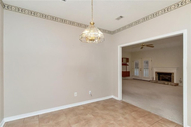 empty room with ceiling fan with notable chandelier, a fireplace, and carpet flooring