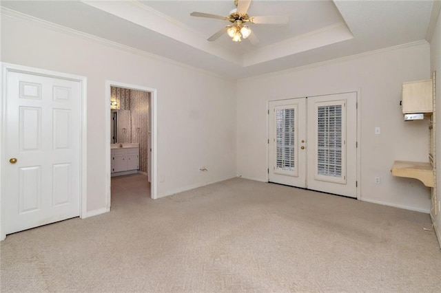 spare room with ceiling fan, a tray ceiling, ornamental molding, light colored carpet, and french doors