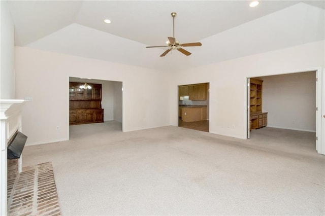 unfurnished living room featuring a fireplace, light colored carpet, a raised ceiling, and ceiling fan