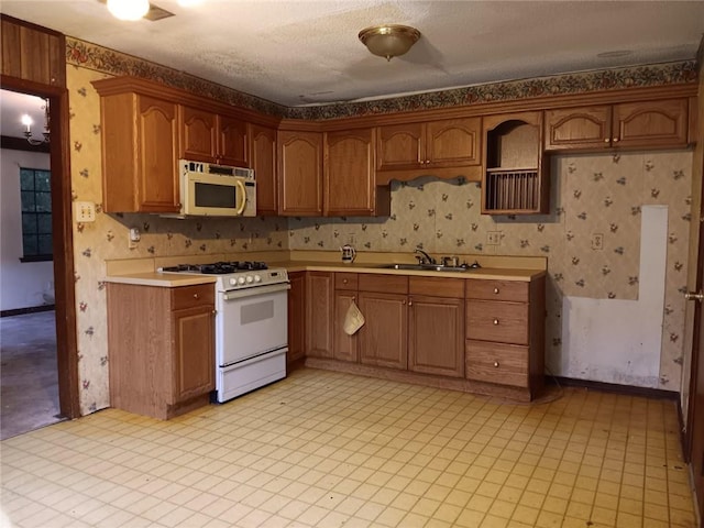 609 Gehrig Ave, Prichard, AL 36610 - kitchen featuring white appliances, wallpapered walls, light countertops, and brown cabinets