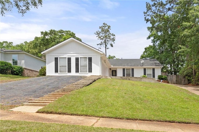 single story home with fence, gravel driveway, and a front yard