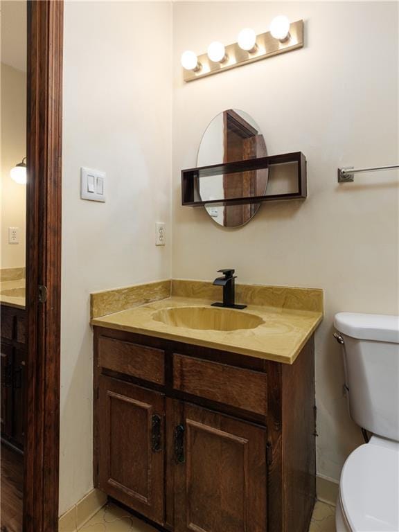 half bath featuring toilet, baseboards, and vanity