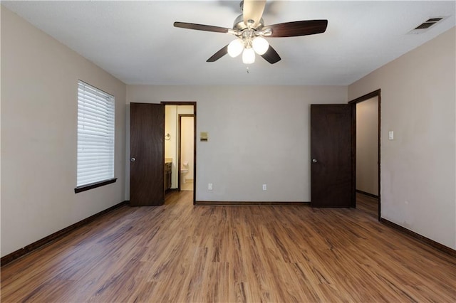 unfurnished bedroom with hardwood / wood-style floors, ceiling fan, and ensuite bath