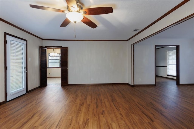 unfurnished room with a wealth of natural light, ornamental molding, wood finished floors, and visible vents