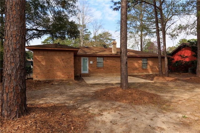 back of property with a patio area, a chimney, and brick siding