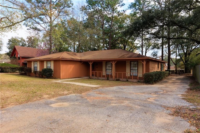 ranch-style house with a porch, a front yard, driveway, and fence