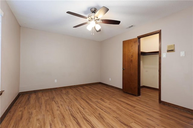 unfurnished bedroom with light hardwood / wood-style flooring, ceiling fan, a spacious closet, and a closet