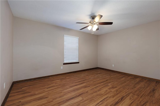 empty room with ceiling fan, baseboards, and wood finished floors