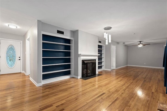 409 Byron Ave E, Mobile, AL 36609 - unfurnished living room with built in shelves, ceiling fan, a fireplace, and light wood-style flooring