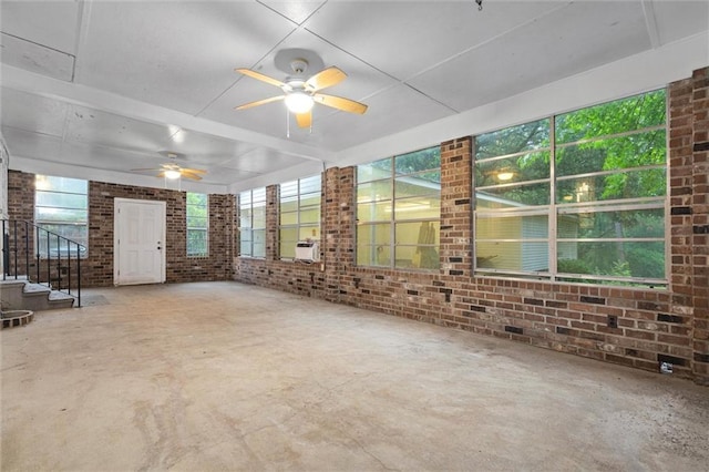 409 Byron Ave E, Mobile, AL 36609 - unfurnished living room with brick wall, stairs, a ceiling fan, and concrete floors