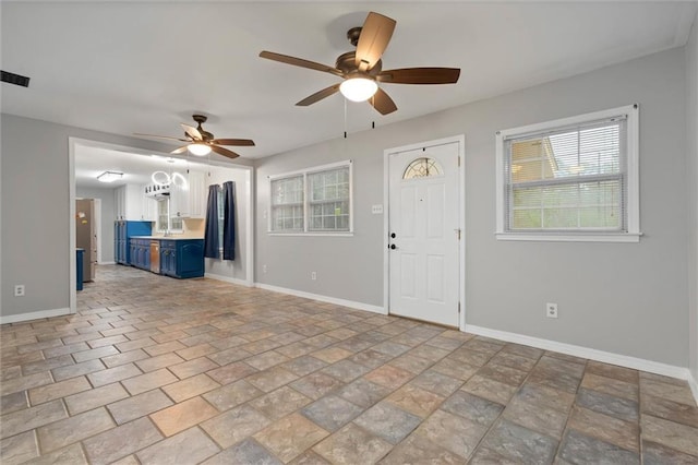 409 Byron Ave E, Mobile, AL 36609 - unfurnished living room featuring ceiling fan, plenty of natural light, and light stone finish flooring