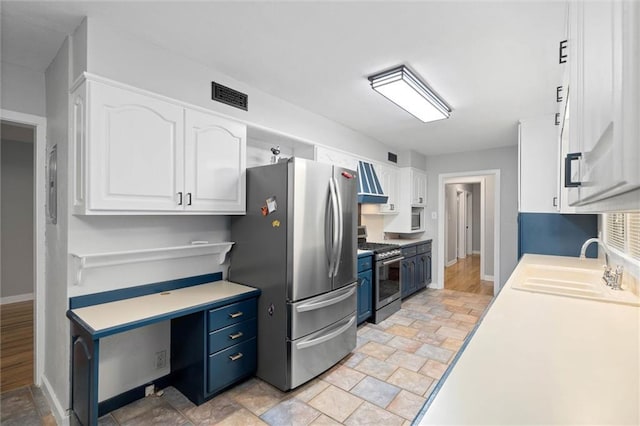409 Byron Ave E, Mobile, AL 36609 - kitchen with appliances with stainless steel finishes, white cabinetry, light countertops, blue cabinets, and light stone finish flooring