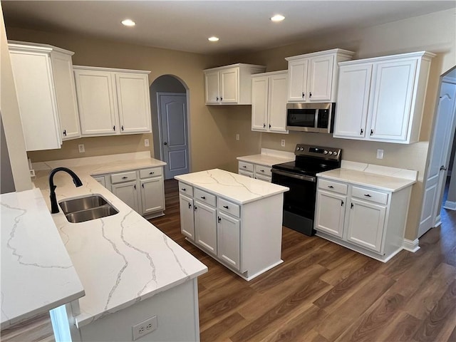 kitchen featuring a kitchen island, sink, black range with electric cooktop, light stone countertops, and white cabinetry