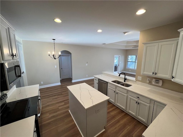 kitchen featuring sink, light stone countertops, dark hardwood / wood-style flooring, and a center island