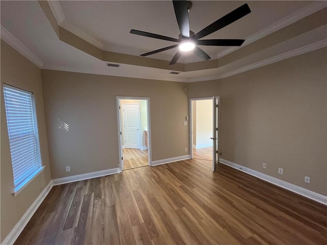 unfurnished room featuring wood-type flooring, crown molding, a tray ceiling, and ceiling fan