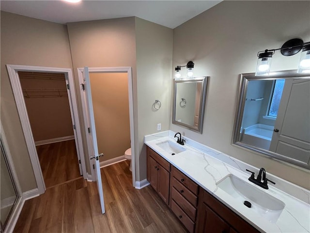 bathroom with a shower with door, hardwood / wood-style floors, vanity, and toilet